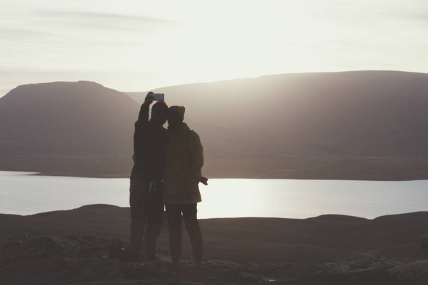 Fotograaf en wandelaar op een rotsachtige klif tijdens de zonsondergang. Grote - Foto, afbeelding