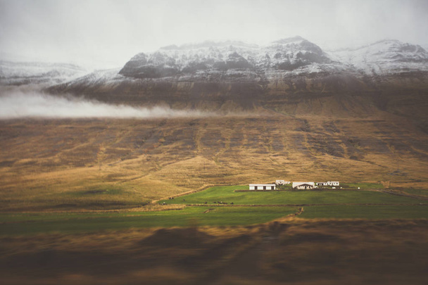 Αγρόκτημα μπροστά από ένα άδειο οροσειρά με ομίχλη και το χιόνι. Φανταστικές - Φωτογραφία, εικόνα