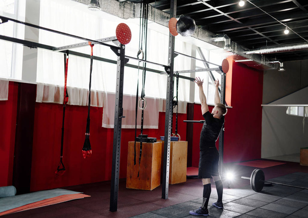 Homme musculaire faisant de l'exercice avec le ballon de médecine dans la salle de gym. Jeune homme faisant l'exercice du haut du corps travaillant avec une balle lourde pondérée
 - Photo, image
