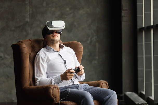 Man wearing virtual reality goggles watching movies or playing video games. The vr headset design is generic and no logos - Foto, Imagem