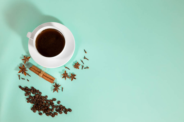 Чашка кофе, кардамон, зерна кофе и корицы на бирюзовом фоне
 - Фото, изображение