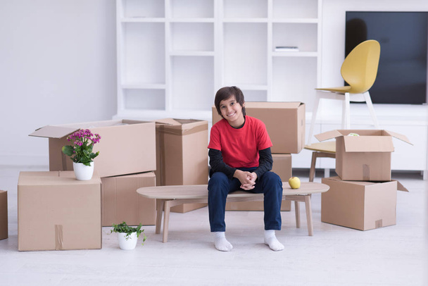 boy sitting on the table with cardboard boxes around him - Φωτογραφία, εικόνα