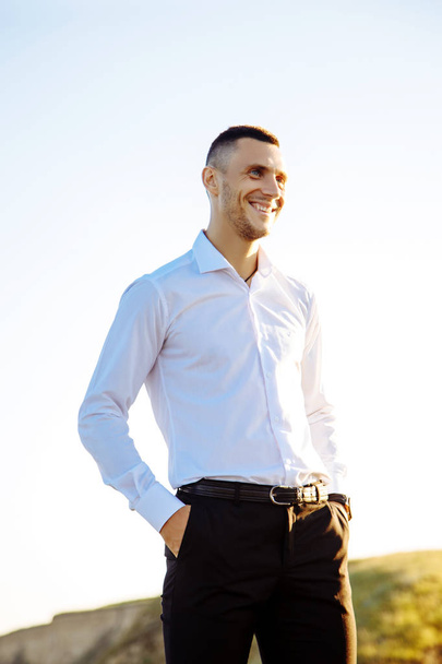 Cheerful young man athlete in white shirt standing near the sea - Valokuva, kuva