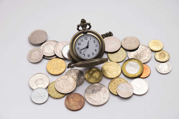 viejo reloj de bolsillo de plata que pone en varios tamaños pila de monedas con fondo blanco, esta imagen para el ahorro de dinero y el concepto retro
 - Foto, imagen