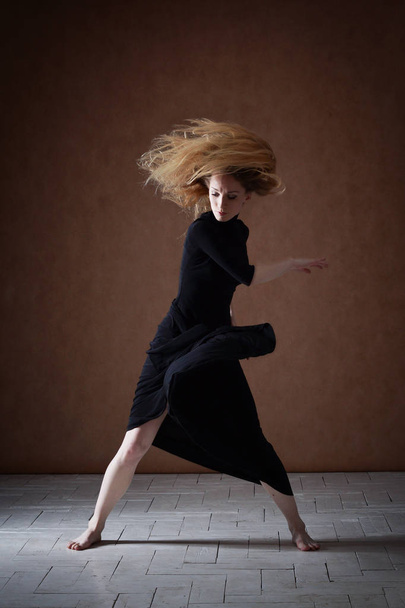 Modern ballet dancer posing on dark background - Фото, изображение