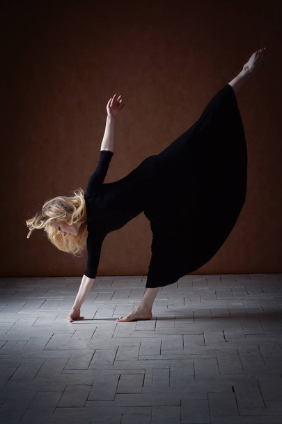 Moderni baletti tanssija poseeraa tummalla taustalla
 - Valokuva, kuva