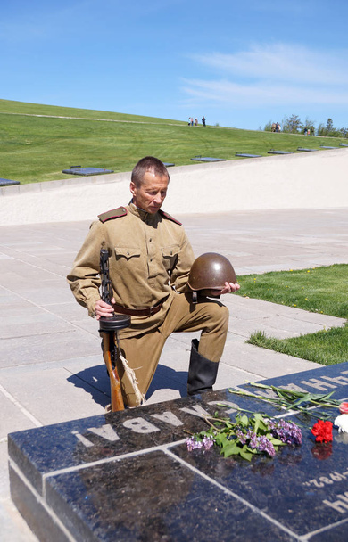 Fighter of Red Army bent a knee at a gravestone with an inscript - Photo, Image