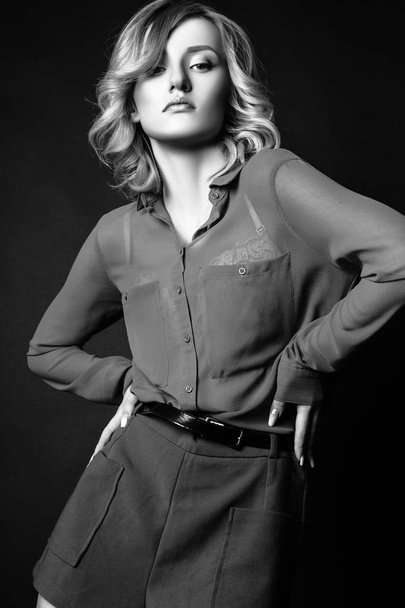 Studio photo of young curly blonde woman on black background. Black and white - Valokuva, kuva