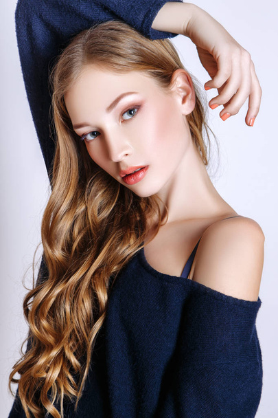 Fashion portrait of beautiful young woman with blond hair. Girl in a blue pullover and jeans on a white background - Φωτογραφία, εικόνα