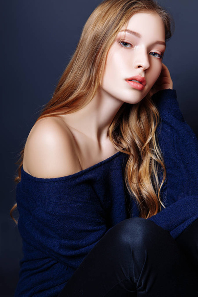 Fashion portrait of beautiful young woman with blond hair. Girl in a a blue pullover on a black background - Foto, Imagem