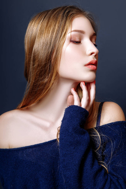 Fashion portrait of beautiful young woman with blond hair. Girl in a a blue pullover on a black background - Foto, Imagem