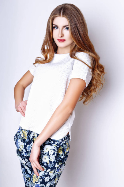 Fashion portrait of beautiful young woman with long hair. Girl in a white blouse and pants on a white background - Fotografie, Obrázek