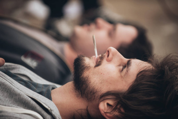 Two friends lying on the ground and smoke grass - Foto, Bild