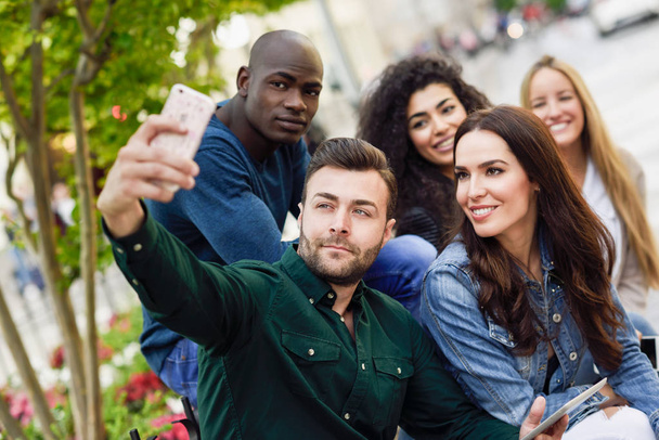 Jóvenes multiétnicos tomando selfie juntos en el contexto urbano
 - Foto, imagen