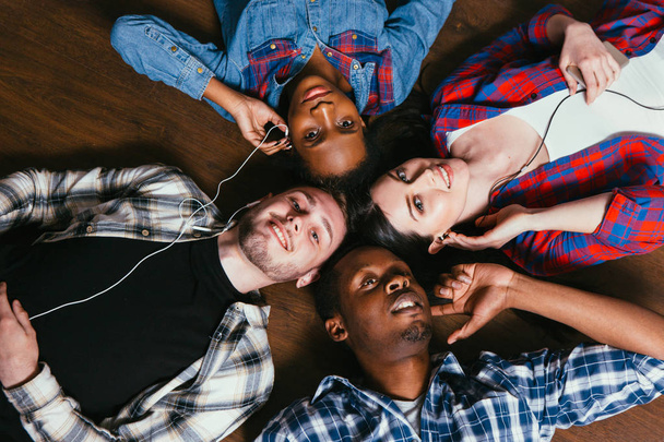 Four friends listen music together, lay on floor - Photo, Image