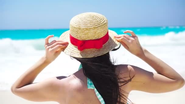 Vissza kilátás gyönyörű nő kalap a nyári szünetben a fehér tengerparton. - Felvétel, videó