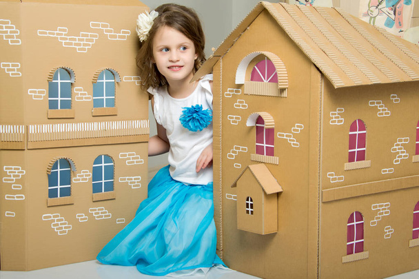Little girl playing in a cardboard house. - Fotó, kép