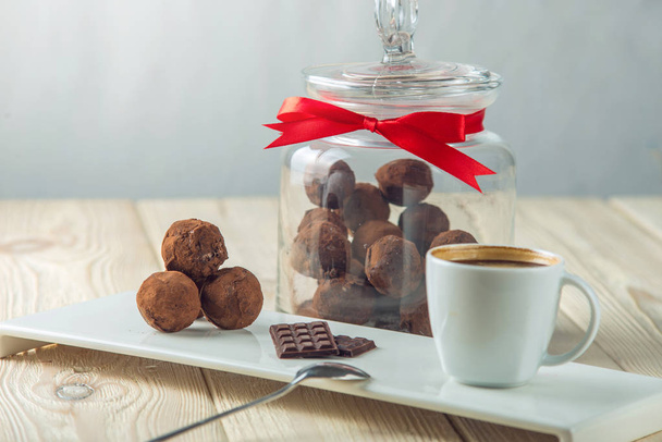 Boules de chocolat truffes sur une soucoupe à côté d'un pot de bonbons et une tasse de café. Le concept de délicieux desserts cadeaux
 - Photo, image