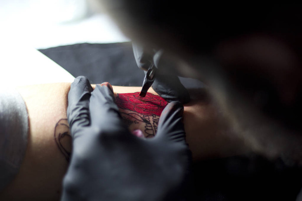 Татуировщик делает татуировку на руке женщины
 - Фото, изображение