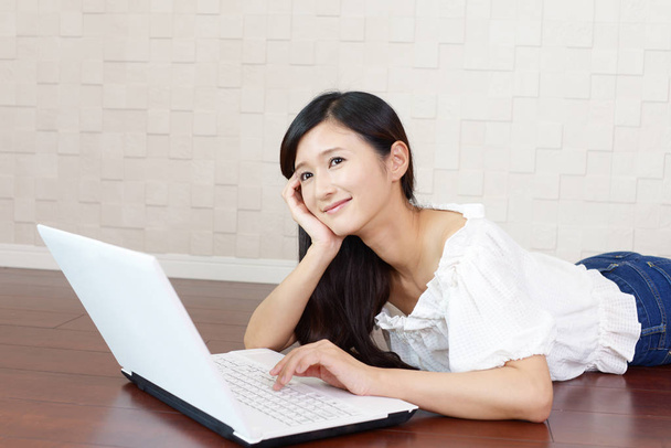 Hymyilevä nainen kannettavan tietokoneen avulla
 - Valokuva, kuva