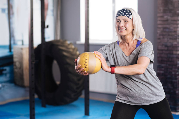 Delighted aged woman working out with a ball - 写真・画像