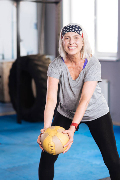 Delighted aged woman exercising with a ball - Фото, зображення