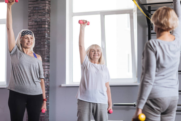 Pleasant sporty women exercising in a fitness club - Zdjęcie, obraz