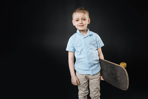 Serious little male person posing with skateboard - Photo, Image