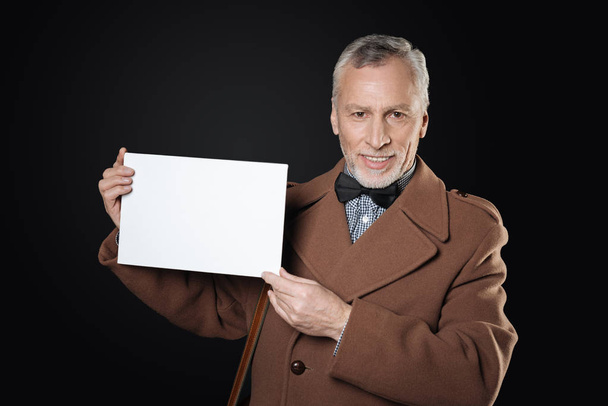 Uśmiechnięty mężczyzna utrzymanie arkuszu białego papieru w obie ręce - Zdjęcie, obraz