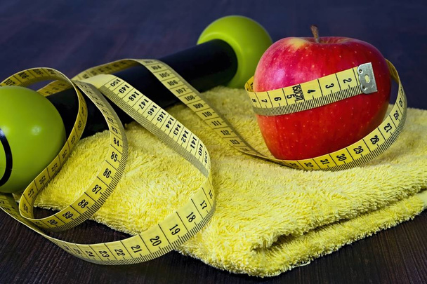 Red apple with measuring tape on a yellow towel. - Photo, Image