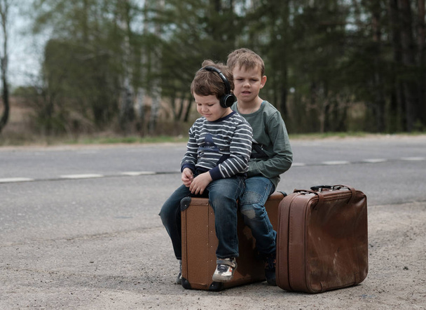 Two boys of European appearance sitting on suitcases - Foto, Imagen
