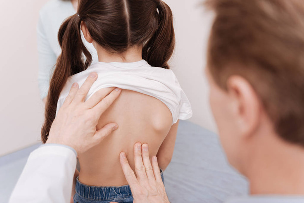 Gentle neat rheumatologist making sure girls spine being healthy - 写真・画像