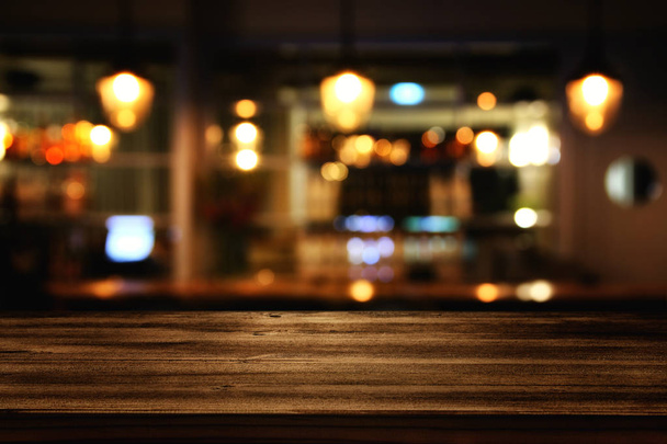wooden table in front of abstract blurred restaurant lights - Foto, Bild