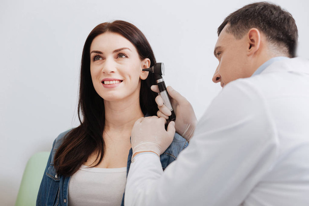 Attentive doctor doing ear exam of pretty woman - Foto, imagen
