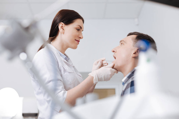 Médico competente olhando para a boca de seu paciente
 - Foto, Imagem