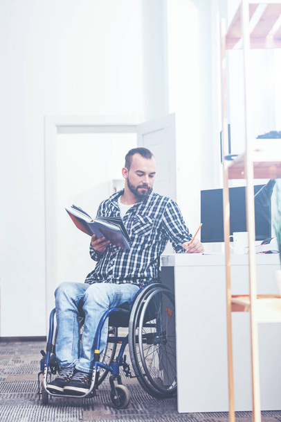 Concentrated handicap enjoying reading book indoors - Foto, Bild