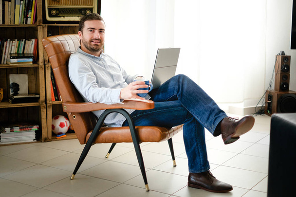 Ο άνθρωπος που εργάζεται στο σπίτι, χρησιμοποιώντας το laptop και wi-fi σύνδεση στο internet - Φωτογραφία, εικόνα