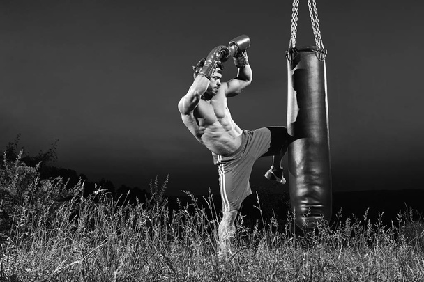 Monochrome shots of a male boxer training with a punching bag ou - Фото, изображение