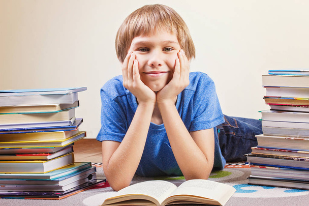 Lächelnder Junge zwischen Bücherstapeln. - Foto, Bild