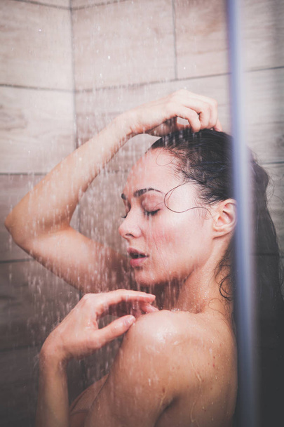 Young beautyful woman under shower in bathroom - 写真・画像