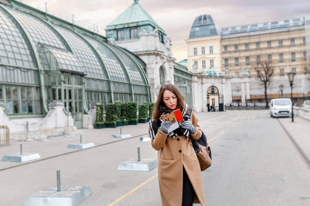 schöne junge Frau spaziert durch Wien, Österreich und liest Büchlein mit Karte - Foto, Bild