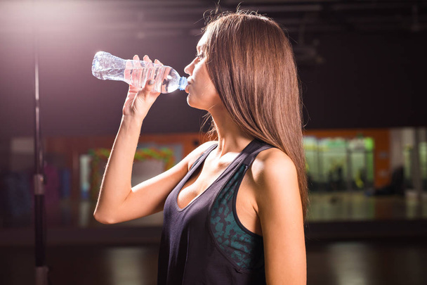 Perfil da mulher bonita que vai beber um pouco de água de garrafa de plástico após o treino
 - Foto, Imagem