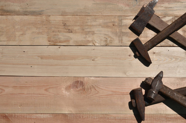Unos cuantos martillos oxidados yacen sobre una mesa de madera en un taller
 - Foto, Imagen
