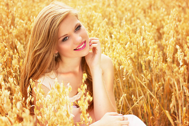 Czyste piękno. Portret młodą i atrakcyjną uśmiechający się rudowłosy dziewczyna ubrana w białą sukienkę pozowanie w polu pszenicy żółty. - Zdjęcie, obraz
