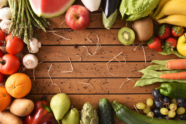 Groenten en fruit rond een houten tafelblad bekijken - Foto, afbeelding