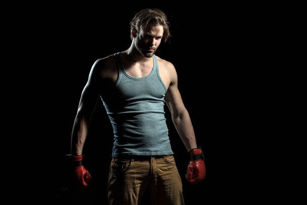 Poważny facet w czerwone rękawice bokserskie. Muskularny mężczyzna w szary T-shirt przygotowuje się do bitwy. Bokser na ringu. Atrakcyjny facet sportowca z czerwone rękawice - Zdjęcie, obraz