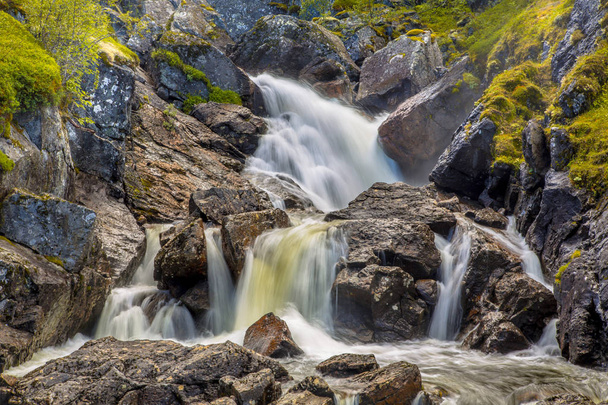 Nahaufnahme eines Wasserfalls mit Langzeitbelichtung und verschwommenem Wasserfluss - Foto, Bild