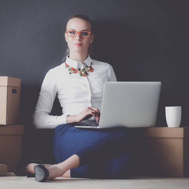 Woman sitting on the floor near a boxes with laptop - Φωτογραφία, εικόνα