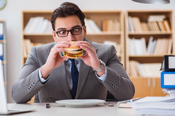 Hungry funny businessman eating junk food sandwich - Fotó, kép