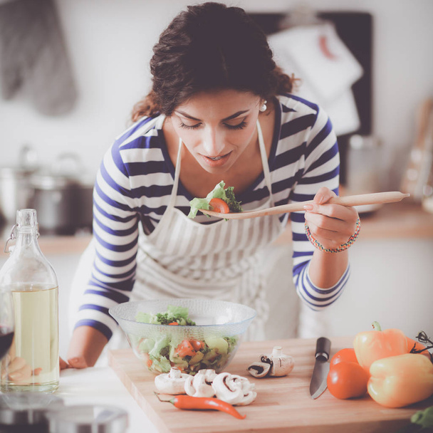 Young woman eating fresh salad in modern kitchen - Fotoğraf, Görsel